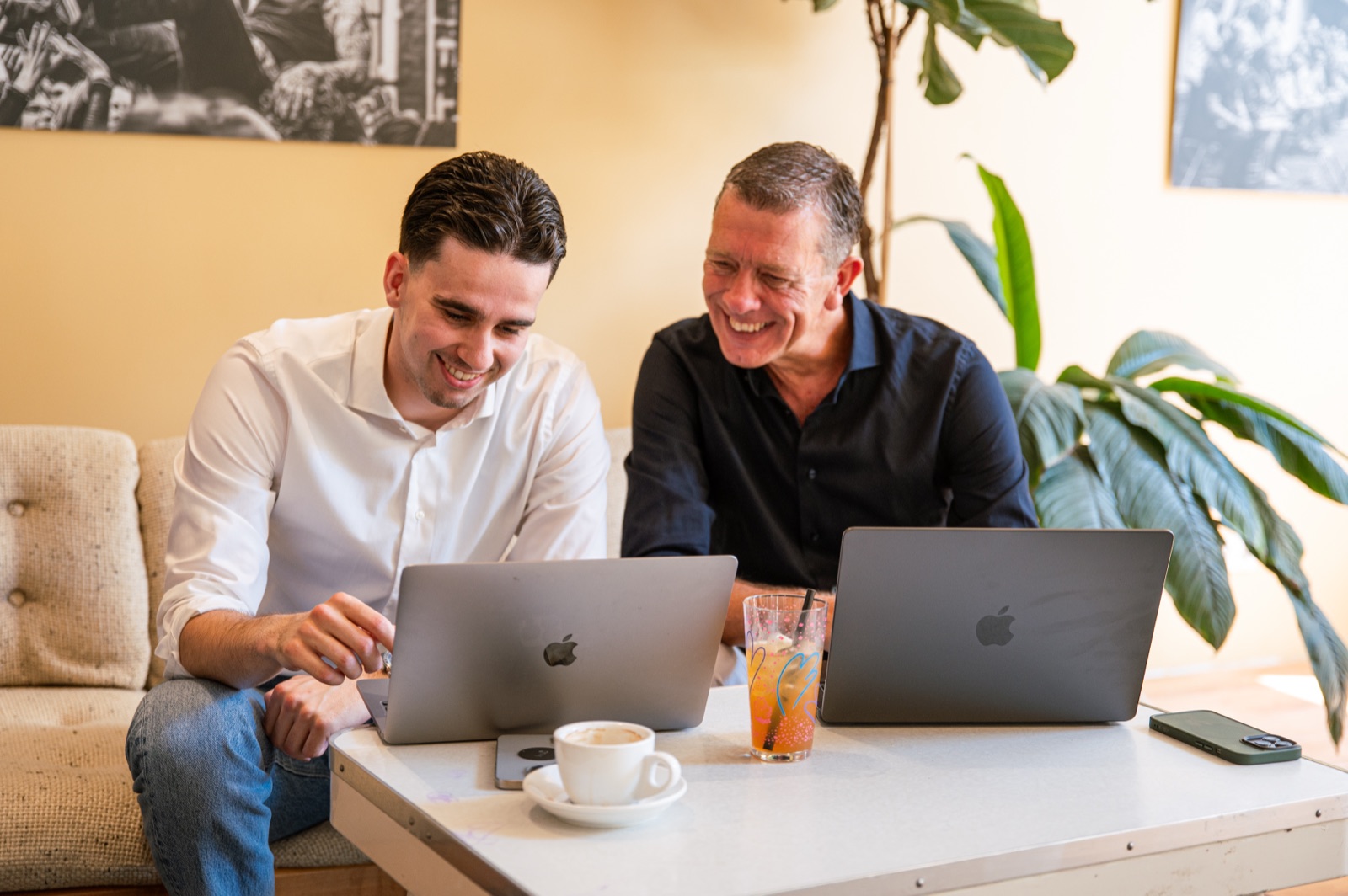 Luca en Tim lachend achter hun laptops tijdens een werksessie